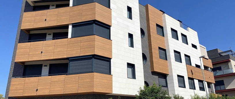 Wohnhaus mit Holzpaneelen an Balkonen und kontrastreicher Fassade.