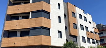 Wohnhaus mit Holzpaneelen an Balkonen und kontrastreicher Fassade.