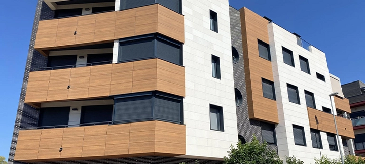 Wohnhaus mit Holzpaneelen an Balkonen und kontrastreicher Fassade.