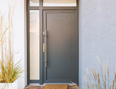 Graphitfarbene Eingangstür eines Hauses mit seitlichen und oberen Glaselementen für zusätzliches Licht.