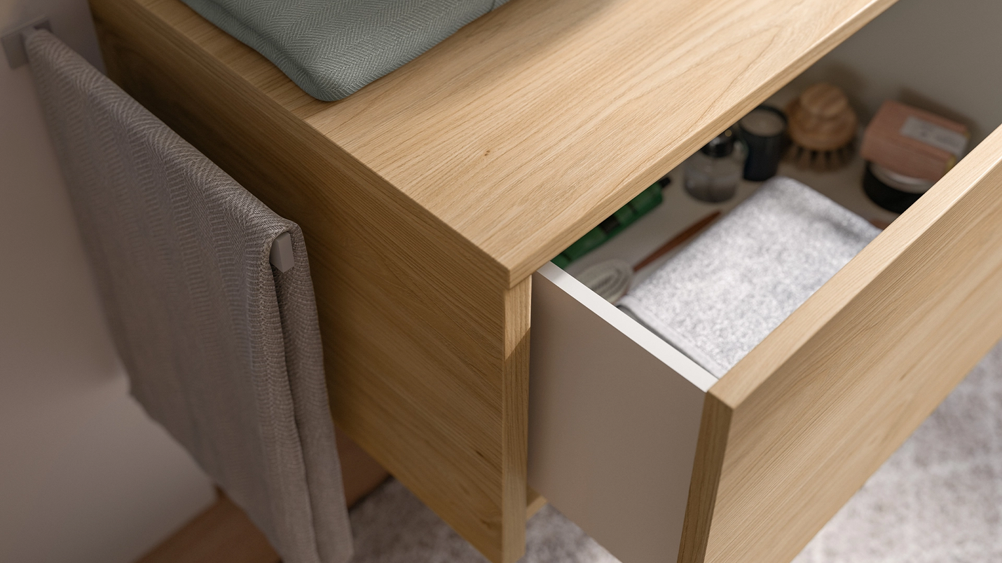 Badezimmermöbel in heller Holzoptik mit halb geöffneter Schublade, Handtuchhalter und Badutensilien.