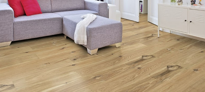 Im Wohnzimmer ist Parkett in Langdielen-Optik verlegt. Dazu passt ein Ecksofa mit bunten Kissen.