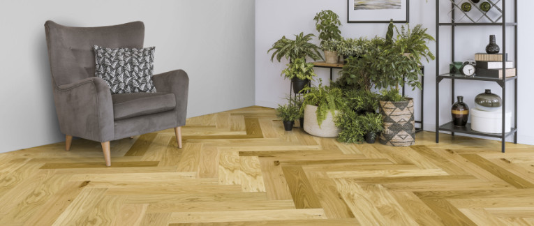 Wohnbereich mit hellem Fischgrätenparkett ausgelegt.