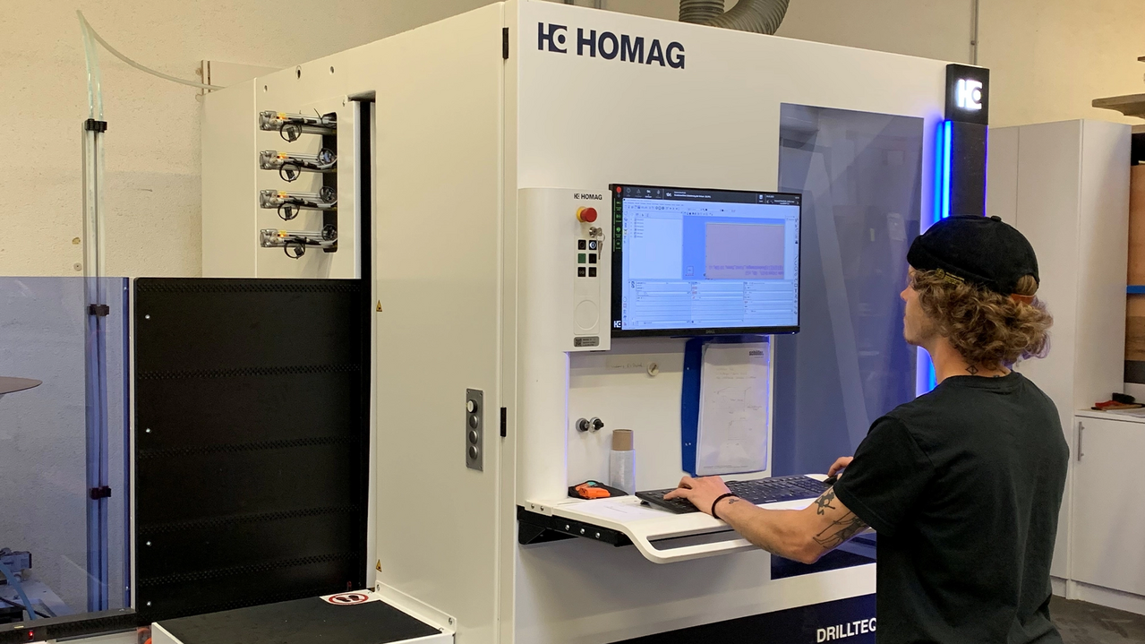 Mitarbeiter bedient eine HOMAG CNC‑Maschine am Monitor und Bedienpult in einer Werkstatt.