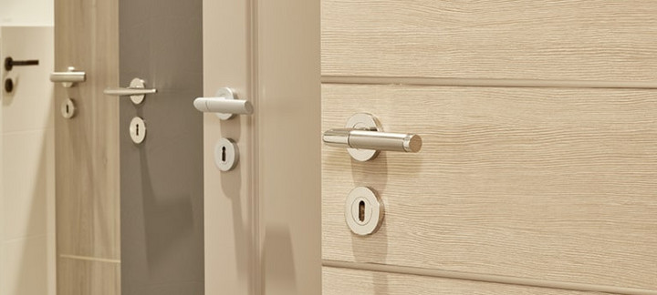 Mehrere nebeneinander angeordnete Türblätter in unterschiedlichen Farbtönen (weiß, holzähnlich, grau) mit integrierten Türgriffen.