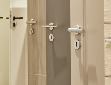 Mehrere nebeneinander angeordnete Türblätter in unterschiedlichen Farbtönen (weiß, holzähnlich, grau) mit integrierten Türgriffen.